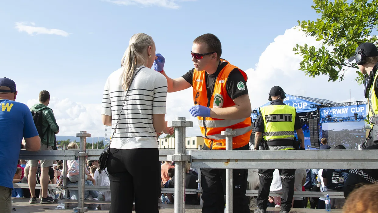 Mathias Emil Lundbye fra Norsk Folkehjelp Rena hjelper en tilskuer under åpningskonserten.
