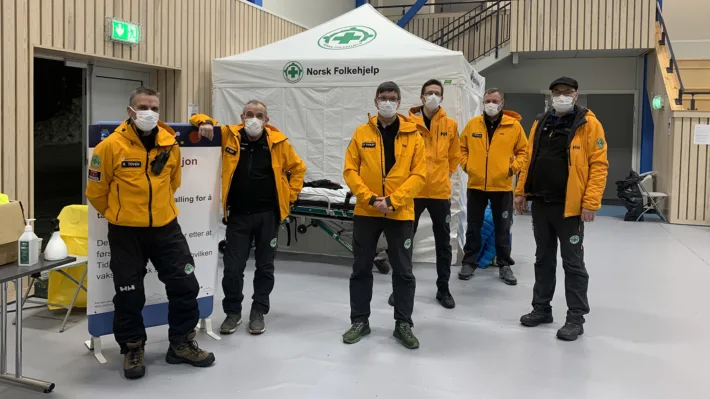 Frivillige fra Norsk Folkehjelp Sanitet Nesset på vakt under vaksinering i Nessethallen i Molde Kommune. De seks mannskapene bidrar med veiledning, mottak og observasjon.