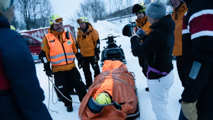 Steve Skare i Norsk Folkehjelp Tromsø viser hvordan man frakter en pasient trygt på båre under vinterforhold.