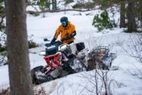 Et mannskap kjører scooter i skogen med slede og båre