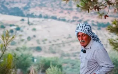 Farid Muqbil ser inn i kameraet med området han bodde i bakgrunnen.