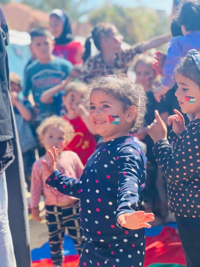 Liten jente med en palestinsk flagg på kinnet smiler