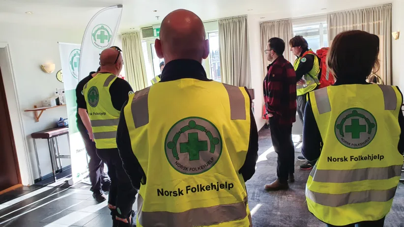 Bildet viser ansatte og frivillige som er samlet for en gjennomgang av rutinene på hotellet.