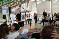 Solidaritetsauksjon er god stemning! Auksjonarius Christer Holm og frivillig i Norsk Folkehjelp, Linda Træet, presenterer ett av de 130 verkene som ble donert av engasjerte kunstnere.