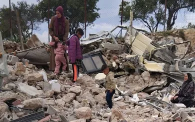 En familie sitter på ruinen av det som tidligere var deres hus