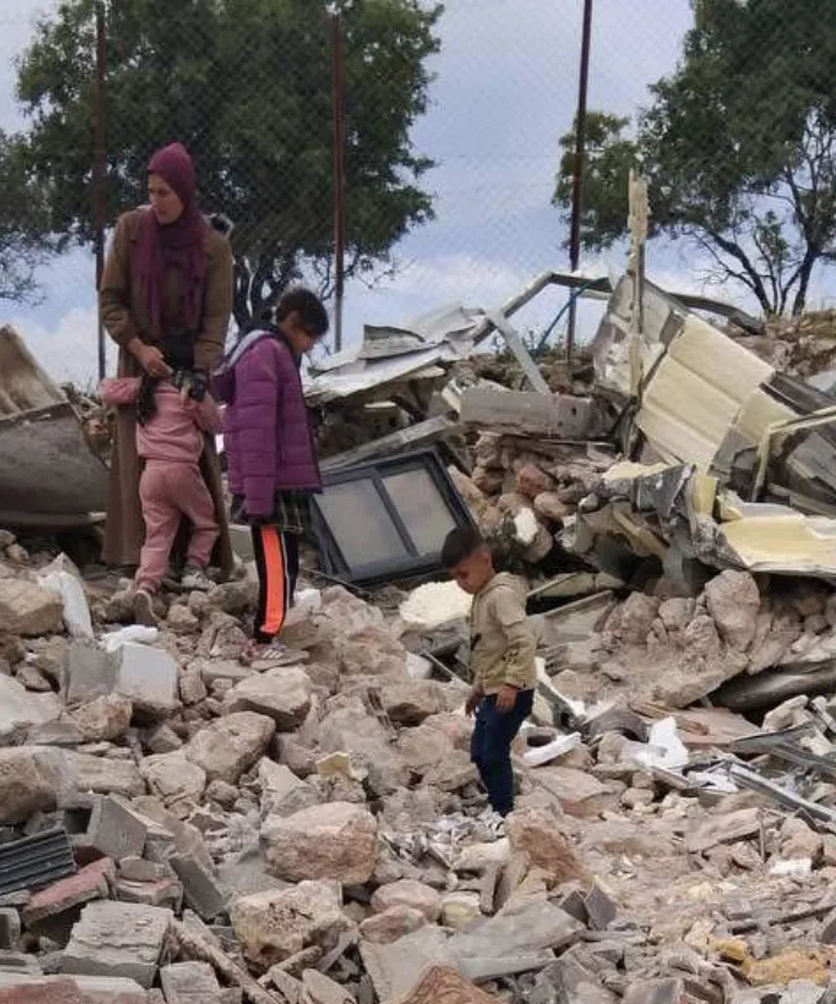 En familie sitter på ruinen av det som tidligere var deres hus