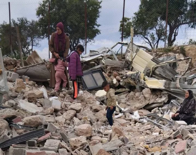 En familie sitter på ruinen av det som tidligere var deres hus